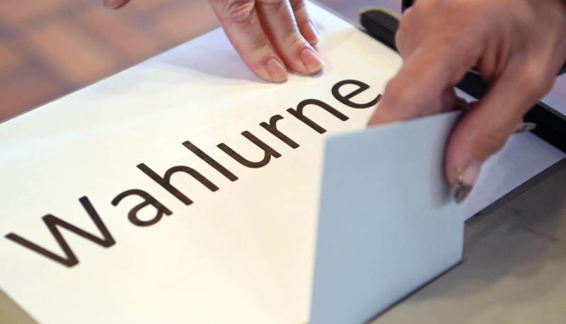 In einem Wahllokal wird ein Stimmzettel in eine Wahlurne geworfen.