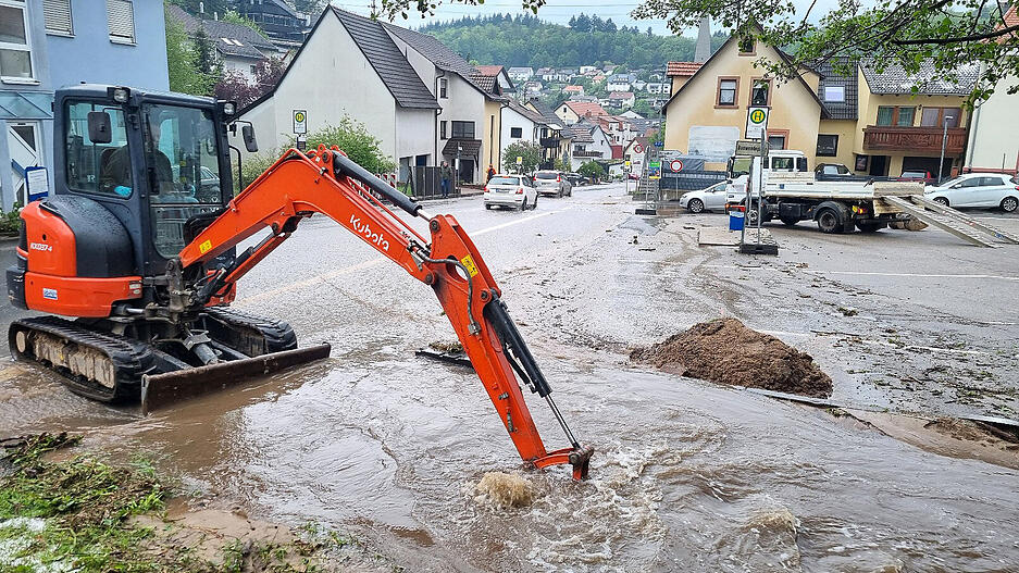 Mit einem kleinen Bagger wird im Stadtteil Altenbach versucht, den Bestbach freizuschaufeln, um das Wasser von der überfluteten Straße abfließen zu lassen.