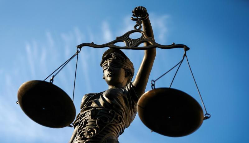 Eine Statue der Justitia hält eine Waage in ihrer Hand.