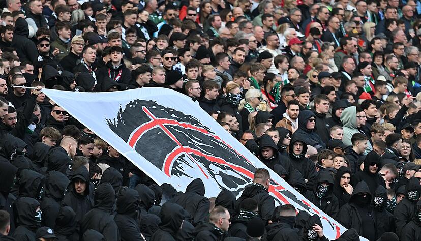 Hannover-Fans halten auf der Tribüne ein Plakat hoch, dass den Kopf von Niedersachsens Innenministerin Daniela Behrens in einem Fadenkreuz zeigt.