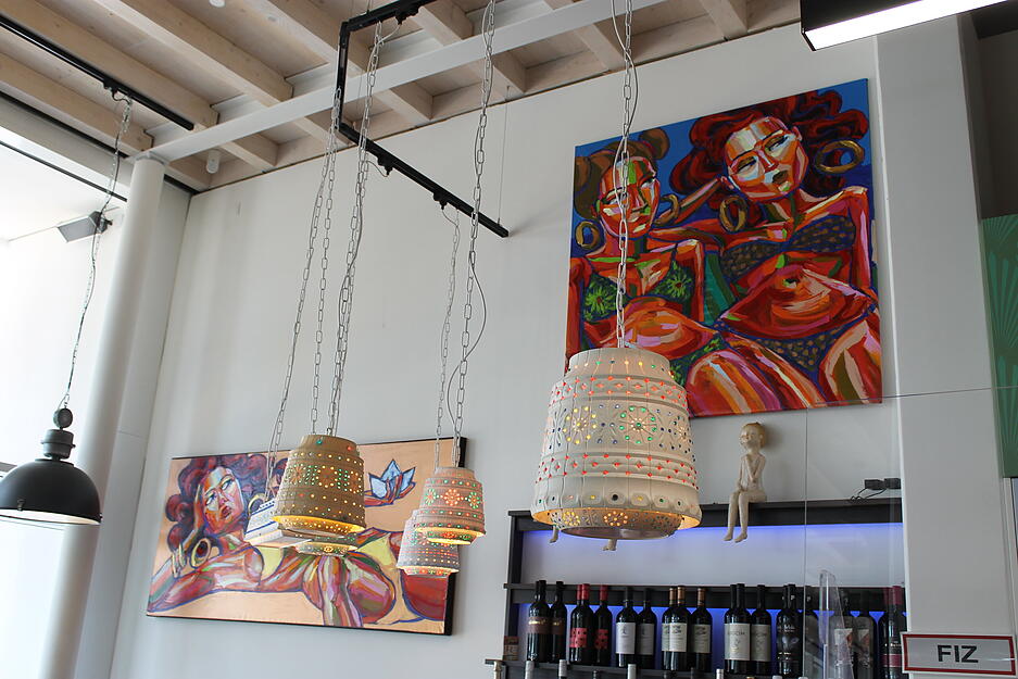 Original Art-Deco-Leuchten und Werke von Robson Reismarques hängen in der Weinbar neben der Hotelrezeption.