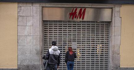 Passanten stehen vor einer geschlossenen H&M-Filiale.