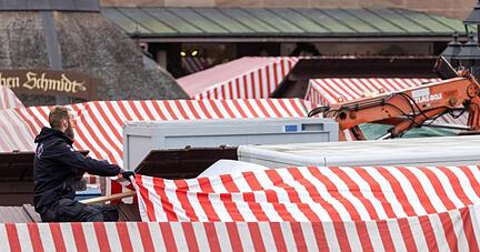Ein Standbetreiber auf dem Nürnberger Christkindlesmarkt platziert rot-weiß gestreifte Dachplane. Ein Standbetreiber auf dem Nürnberger Christkindlesmarkt platziert rot-weiß gestreifte Dachplane.