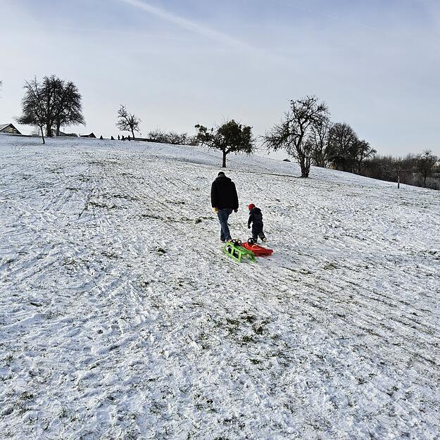 Am Samstag wagen sich ein paar Menschen in Kreuzle-Busch in der Gemeinde Wüstenrot an den schneebedeckten Hügel.
