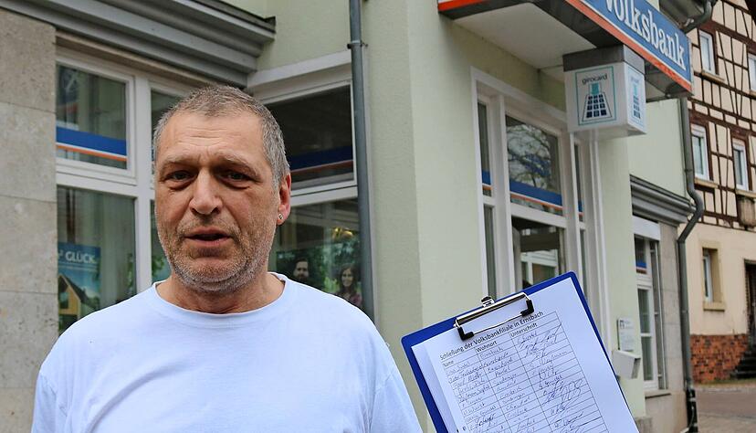 Bäckermeister Rainer Gundel vor der Volksbank-Filiale in der Sindringer Straße in Ernsbach. In der Hand hält er die Unterschriftenliste gegen die Schließung am 1. April 2020. Bis Freitagnachmittag haben 109 Menschen unterschrieben.
Foto: Ralf Reichert Bäckermeister Rainer Gundel vor der Volksbank-Filiale in der Sindringer Straße in Ernsbach. In der Hand hält er die Unterschriftenliste gegen die Schließung am 1. April 2020. Bis Freitagnachmittag haben 109 Menschen unterschrieben.
Foto: Ralf Reichert