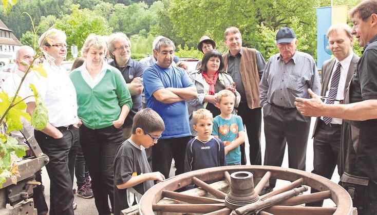 Willi Schmitt (rechts) erläutert, wie der Schmied einst einen Eisenreifen auf ein Holzrad gezogen hat. Foto: Manfred Müller