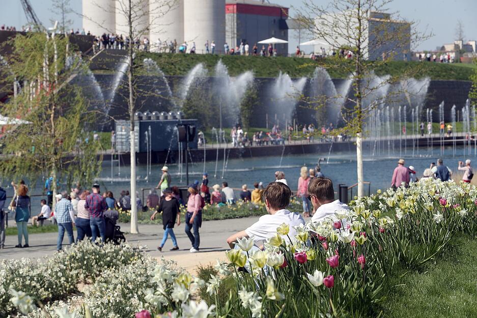Menschen aller Generationen erkunden die Buga. Auch tagsüber gibt es am Karlssee Wasserspiele, richtig bunt wird es aber erst bei Dunkelheit. Bequem sitzen Besucher auf der Sommerinsel und genießen die musikalisch untermalten Wasserspiele.