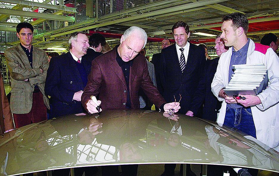 2004: Franz Beckenbauer setzt seinen Namen auf eine Motorhaube.