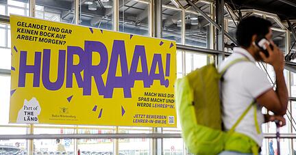 Ein Werbeplakat für den Beruf des Lehrers hängt am Flughafen in Stuttgart.