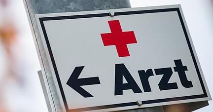 Ein Schild mit der Aufschrift &laquo;Arzt&raquo; h&auml;ngt an einer Stra&szlig;enlaterne.