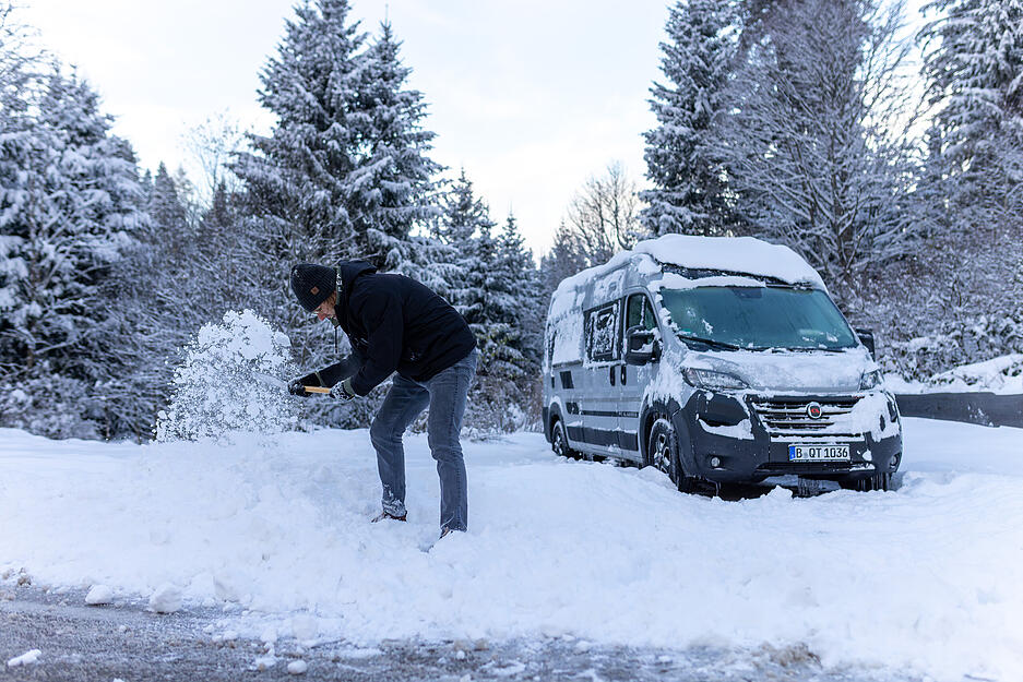 Ein Mann schaufelt nach dem Winter-Einbruch in Baden-Württemberg seinen Bus frei.