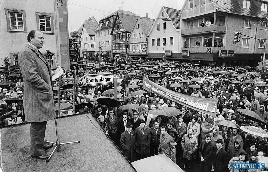 IG-Metall-Bevollmächtigter Klaus Zwickel führt den Kampf vom Dach des Bus-Wartehäuschens auf dem Marktplatz neben dem Rathaus an.