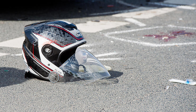 Ein beschädigter Motorradhelm liegt auf einer Straße nach einem schweren Verkehrsunfall.