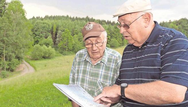 Heinz Tuffentsammer (rechts) und Erwin Stammer mit der Chronik. Im Reichertshäuser Wald hinter ihnen wurde im Jahr 1865 ein Wolf erschossen. Foto: Mario Berger