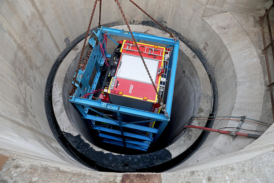 In einem soliden Gestell aus blauen Stahlträgern wird das Feuerwehrauto am Schacht Konradsberg in das Salzbergwerk Heilbronn hinabgelassen.