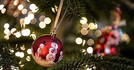 Eine Weihnachtskugel hängt an einem Weihnachtsbaum mit einer Lichterkette. Eine Weihnachtskugel hängt an einem Weihnachtsbaum mit einer Lichterkette.