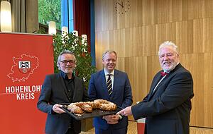 Architekt Martin Ritz (links) &uuml;berreicht Landrat Matthias Neth und Schulleiter Wolfgang Roll einen gebackenen Schl&uuml;ssel.