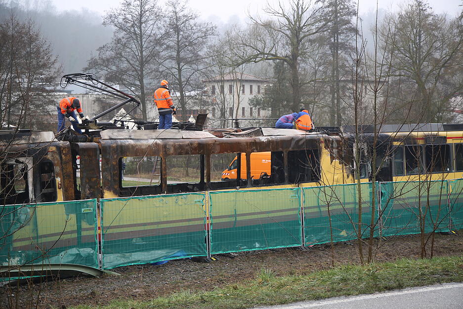 Mitarbeiter der AVG beginnen, die ausgebrannte Stadtbahn in drei Teile zu zerlegen