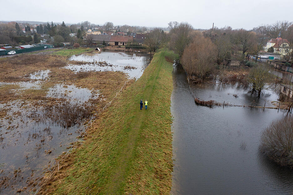 Mitarbeiter des Landesbetriebs für Hochwasserschutz laufen einen Deich ab. Die Ohre in Wolmirstedt im Landkreis Börde ist an einigen Stellen über die Ufer getreten. Erste Straßen sind überflutet, in einigen Straßen drückt das Wasser in die Keller.