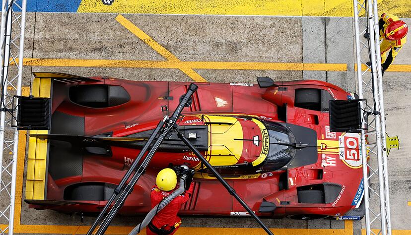 Mechaniker betanken das Auto des Teams Ferrari.