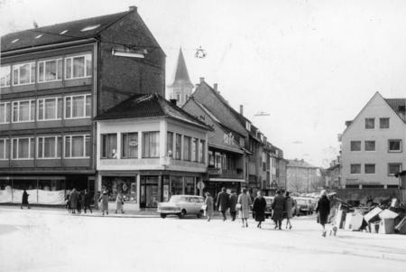 Kiliansplatz 1962.  Ecke Kirchbrunnestraße/Fleiner Straße die Capri Parfümerie und das Modehaus Hippel. Auf der rechten Bildseite sind Steinquader von den Restaurierungsarbeiten an der Kilianskirche zu erkennen.
Foto: Eisenmenger.