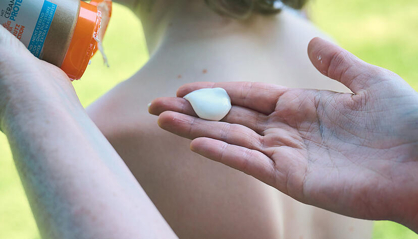 Eine Mutter cremt ihr Kind mit Sonnenschutz ein. (Symbolbild)