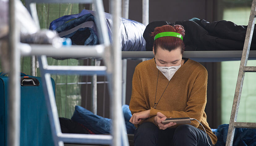 Eine 19-jährige Ukrainerin sitzt auf ihrem Feldbett in einer Notunterkunft und liest auf ihrem Handy die Nachrichten von Freunden. Eine 19-jährige Ukrainerin sitzt auf ihrem Feldbett in einer Notunterkunft und liest auf ihrem Handy die Nachrichten von Freunden.