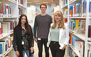 Laura Schmid, Dorian Dickmanns und Leiterin Kathrin Flohr (von links) geben eine F&uuml;hrung durch die Bibliothek.