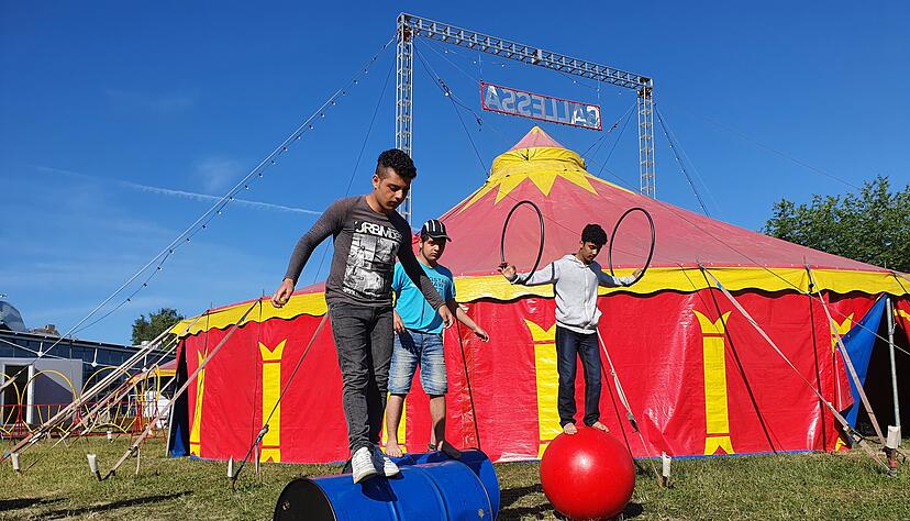 Viel Geschick beweisen die Zwillinge Yassan und Kussay sowie Omar (v.l.) auf den F&auml;ssern und dem Ball vor dem Zelt vom Zirkusprojekt "Circus Ballessa".