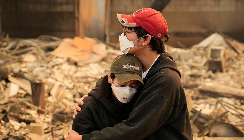Ari Rivera (r) und Anderson Hao umarmen sich vor ihrem zerst&ouml;rten Haus in Altadena. Viele Menschen haben ihr gesamtes Hab und Gut verloren.