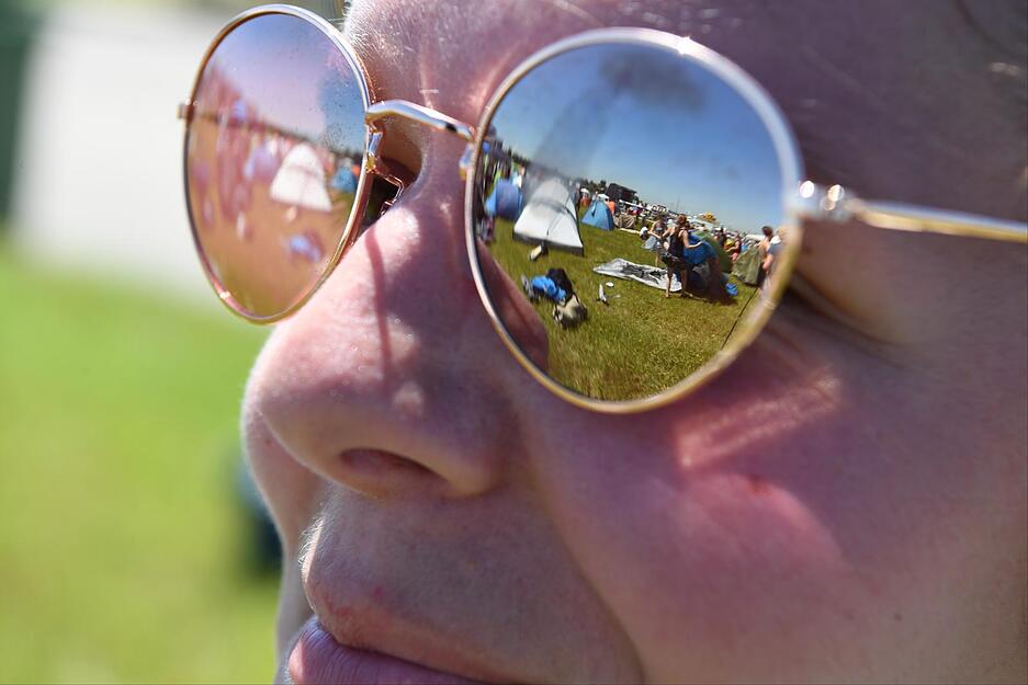 In der Brille einer Festivalbesucherin spiegelt sich einen Tag vor Beginn des Southside-Festivals in Neuhausen das Festivalgel&auml;nde wider.