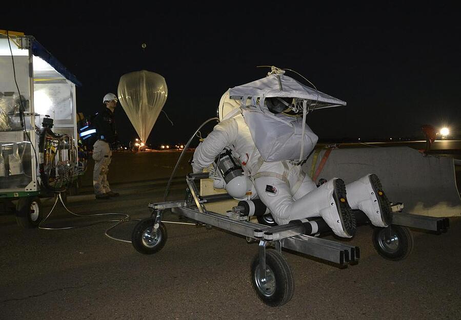 Eustace auf dem Weg zum Helium-Ballon. Der Google-Manager verzichtete im Gegensatz zu Baumgartner auf eine Kapsel und lie&szlig; sich nur in seinem Spezialanzug am Ballon befestigt nach oben bef&ouml;rdern.