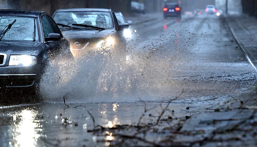09.03.2019, Nordrhein-Westfalen, Gelsenkirchen: Autos fahren langsam durch eine tiefe Pfütze die sich durch Starkregen auf einer Straße gebildet hat. Mit Sturmböen und Gewitter hat Sturmtief Dragi am Samstagnachmittag in Nordrhein-Westfalen für Probleme im Bahnverkehr und auf den Straßen gesorgt. (zu dpa «Sturm sorgt für Zugausfälle im Ruhrgebiet - Autobahn 40 überflutet») Foto: Caroline Seidel/dpa +++ dpa-Bildfunk +++ 09.03.2019, Nordrhein-Westfalen, Gelsenkirchen: Autos fahren langsam durch eine tiefe Pfütze die sich durch Starkregen auf einer Straße gebildet hat. Mit Sturmböen und Gewitter hat Sturmtief Dragi am Samstagnachmittag in Nordrhein-Westfalen für Probleme im Bahnverkehr und auf den Straßen gesorgt. (zu dpa «Sturm sorgt für Zugausfälle im Ruhrgebiet - Autobahn 40 überflutet») Foto: Caroline Seidel/dpa +++ dpa-Bildfunk +++
