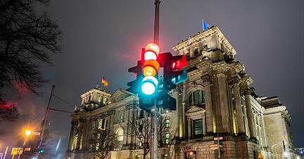 Vor dem Reichstagsgebäude in Berlin, dem Sitz des deutschen Bundestags, leuchtet eine Ampel - durch eine Langzeitbelichtung in allen drei Phasen.