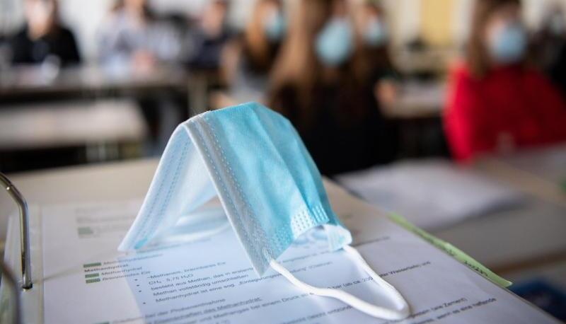 Ein Mund-Nasen-Schutz liegt im Unterricht auf Unterlagen. Themenfoto: dpa Ein Mund-Nasen-Schutz liegt im Unterricht auf Unterlagen. Themenfoto: dpa