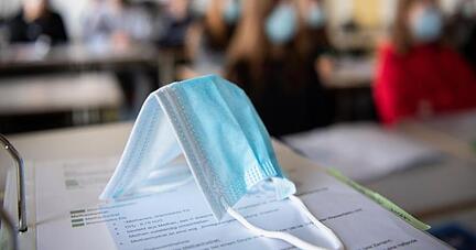 Ein&nbsp;Mund-Nasen-Schutz liegt im Unterricht auf Unterlagen.