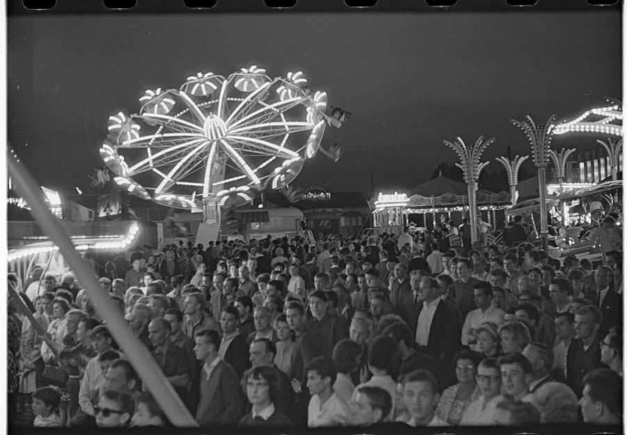 Hell beleuchtete Fahrgeschäfte und viele Besucher zum Volksfest im Juli 1963 auf der Theresienwiese.