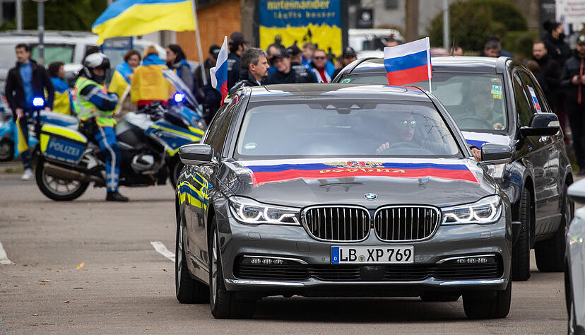 Autos mit Russlandfahnen fahren bei einem Autokorso in Stuttgart unter dem Motto &laquo;Gegen die Diskriminierung russischsprachiger Menschen&raquo; mit. Im Hintergrund ist eine kleine Gegendemonstration mit Pro-Ukrainischen Teilnehmern zu sehen.