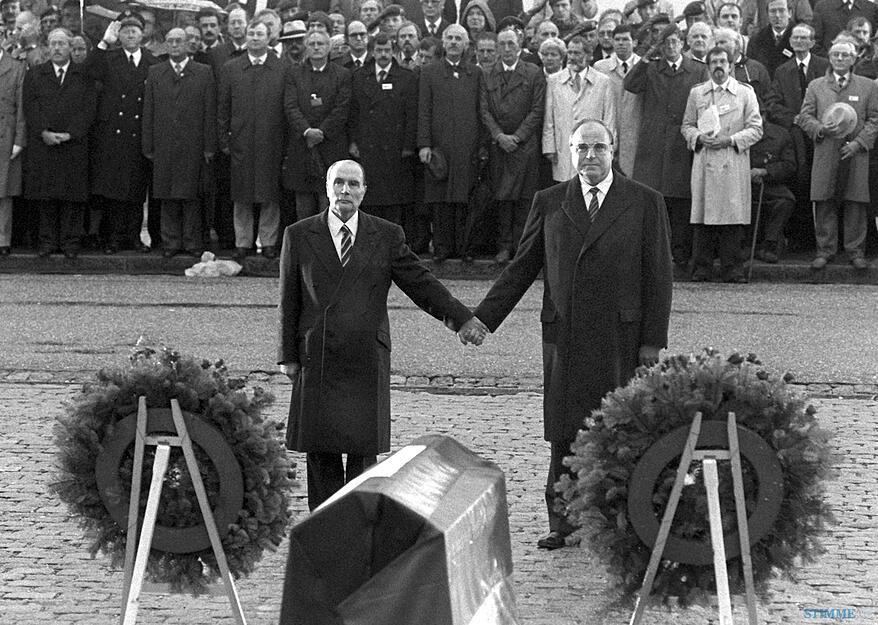 Historische Geste: Der franz&ouml;sische Staatspr&auml;sident Francois Mitterrand (links) und Bundeskanzler Helmut Kohl reichen sich am 22.9.1984 &uuml;ber den Gr&auml;bern von Verdun die Hand. Foto: Archiv/Wolfgang Eilmes/dpa
