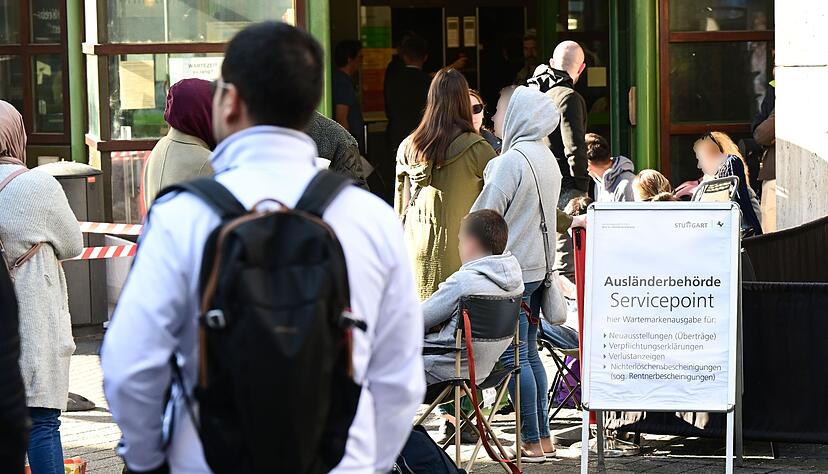 Menschen warten schon Stunden vor der Öffnung vor dem Eingang der Stuttgarter Ausländerbehörde.