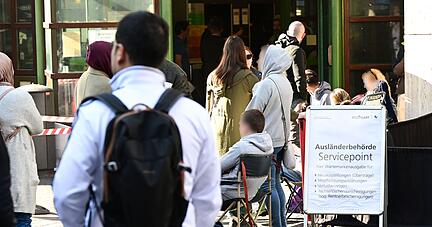 Menschen warten schon Stunden vor der Öffnung vor dem Eingang der Stuttgarter Ausländerbehörde.