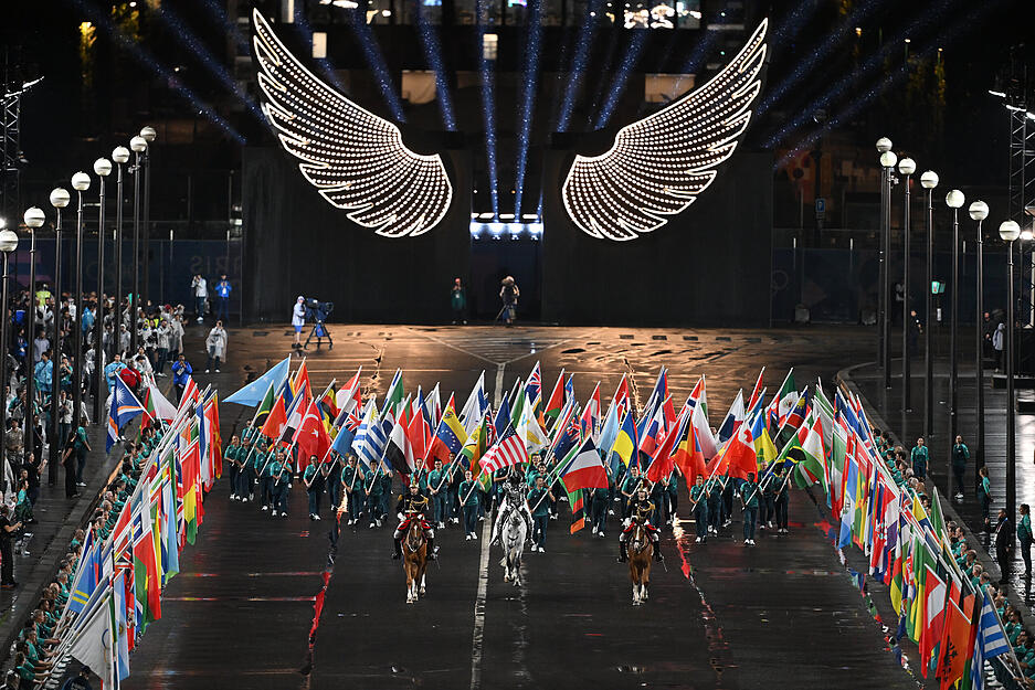 Volunteers tragen die Fahnen der teilnehmenden Nationen auf dem Trocadéro.