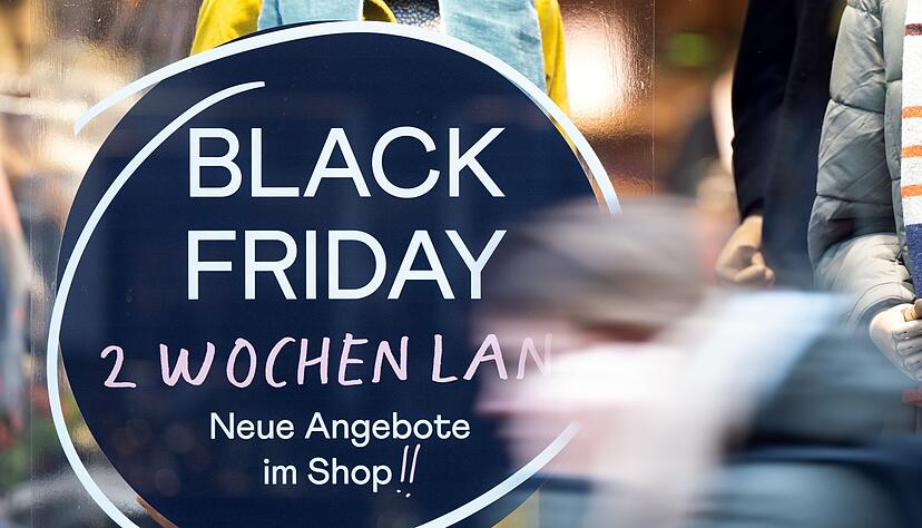 Eine Frau geht an einem Geschäft vorbei, das mit Black Friday-Angeboten wirbt. Eine Frau geht an einem Geschäft vorbei, das mit Black Friday-Angeboten wirbt.