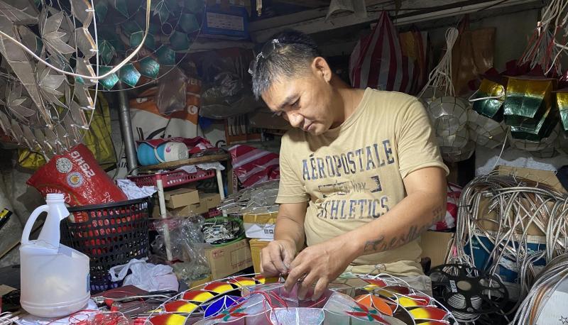 Andrew Flores fügt in seinem kleinen Geschäft für Weihnachtsdekoration im Dorf Elias Aldana nahe Manila Glühbirnen zu einer aus Capiz-Muscheln gefertigten Parole hinzu.
