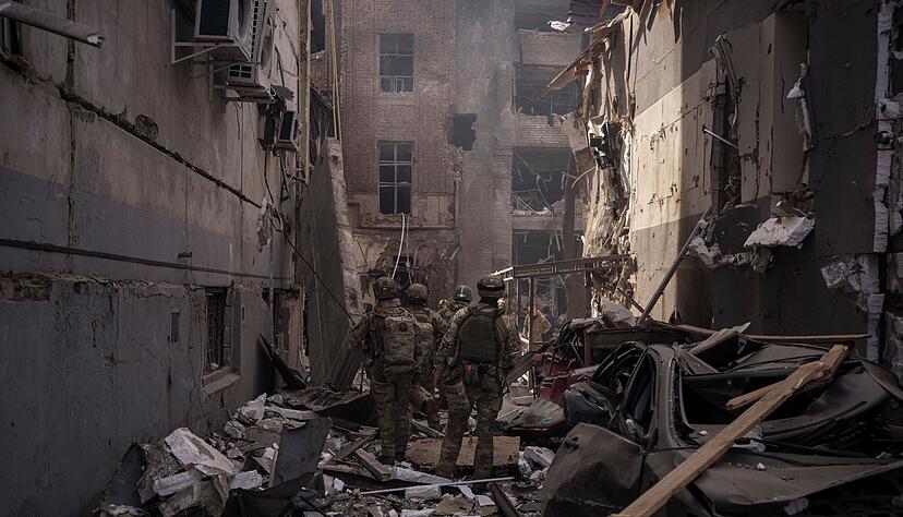 Ukrainische Soldaten gehen zwischen den Tr&uuml;mmern besch&auml;digter Geb&auml;ude nach einem russischen Angriff in Charkiw.