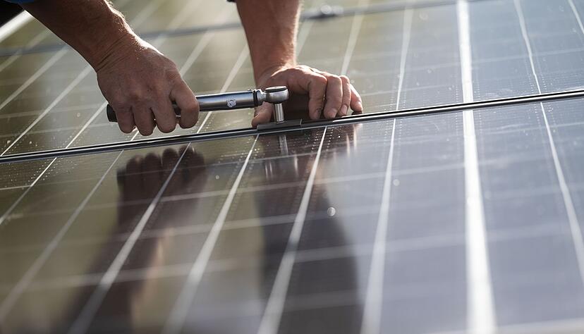 Mitarbeiter einer Firma montieren Photovoltaikmodule auf dem Dach eines Wohnhauses.