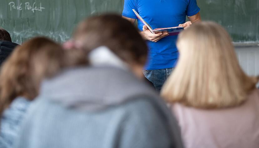 Ein Lehrer steht im Unterricht an der Tafel.