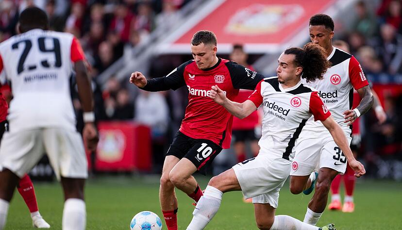 Für den Ex-Leverkusener Florian Wirtz (M) kommt es am Mittwoch zum Wiedersehen mit Eintracht Frankfurt um Arthur Theate (r). (Archivbild) Für den Ex-Leverkusener Florian Wirtz (M) kommt es am Mittwoch zum Wiedersehen mit Eintracht Frankfurt um Arthur Theate (r). (Archivbild)