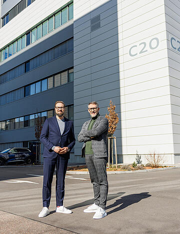 Verantworten bei Audi in Neckarsulm die Verbrenner- und Hochvoltentwicklung: Matthias Honzen (links) und Jens Baumann vor dem Multifunktionsgeb&auml;ude C20.