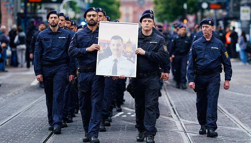 Polizisten tragen bei einem Trauermarsch für den bei einer Messerattacke tödlich verletzten Polizisten Rouven Laur dessen Bild. Polizisten tragen bei einem Trauermarsch für den bei einer Messerattacke tödlich verletzten Polizisten Rouven Laur dessen Bild.